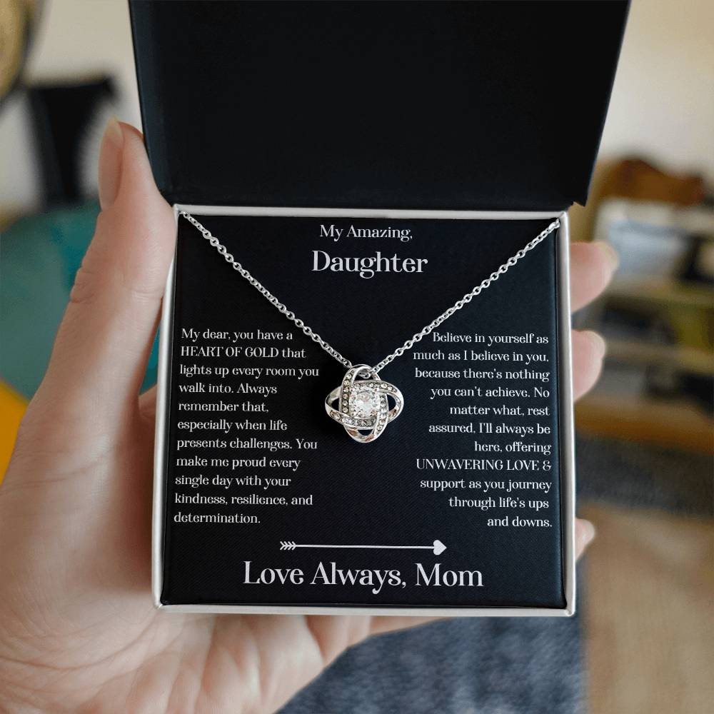 Hand holding Daughter gift from mom with love knot necklace and special message in standard box