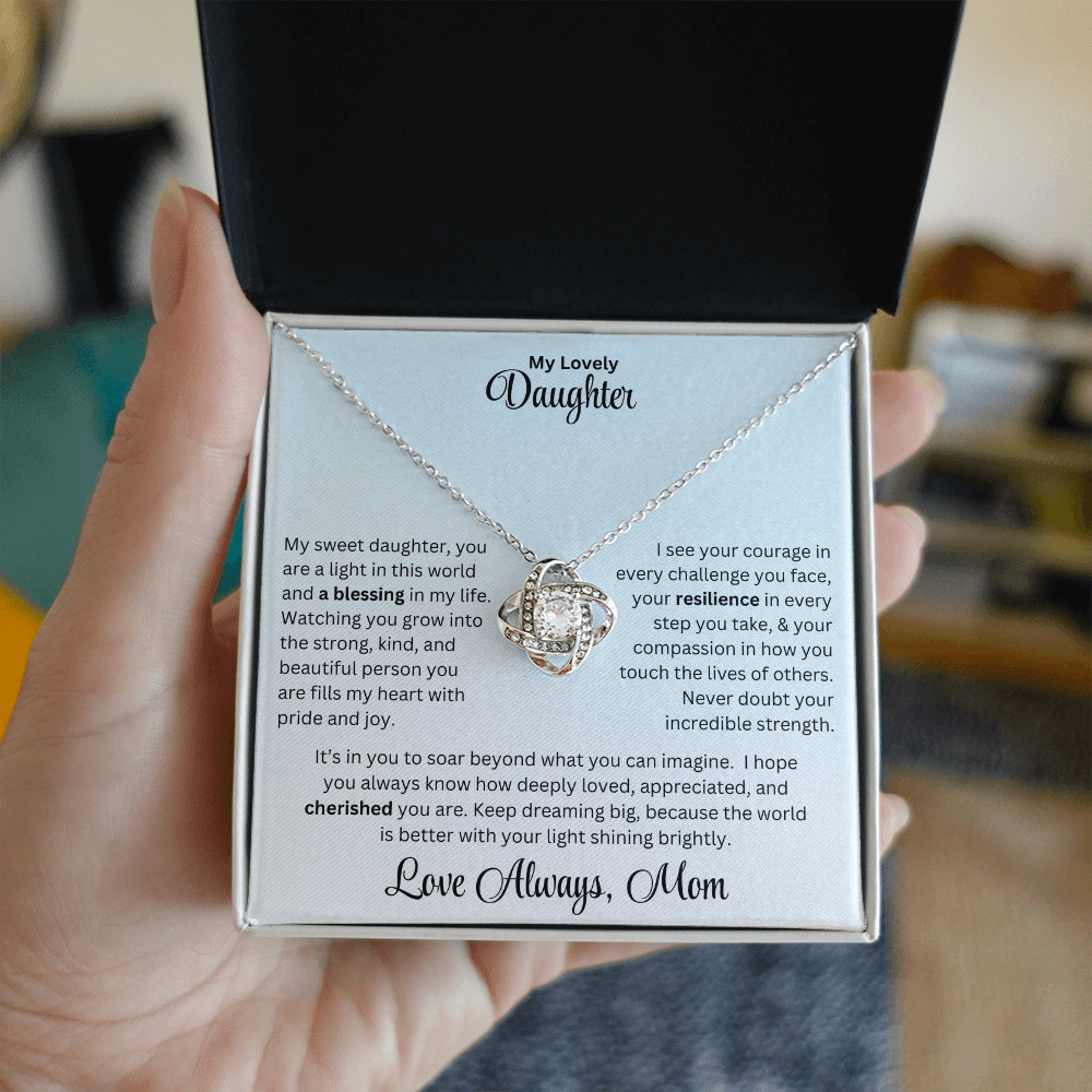 Hand holding Daughter gift from mom with love knot necklace and special message in standard box