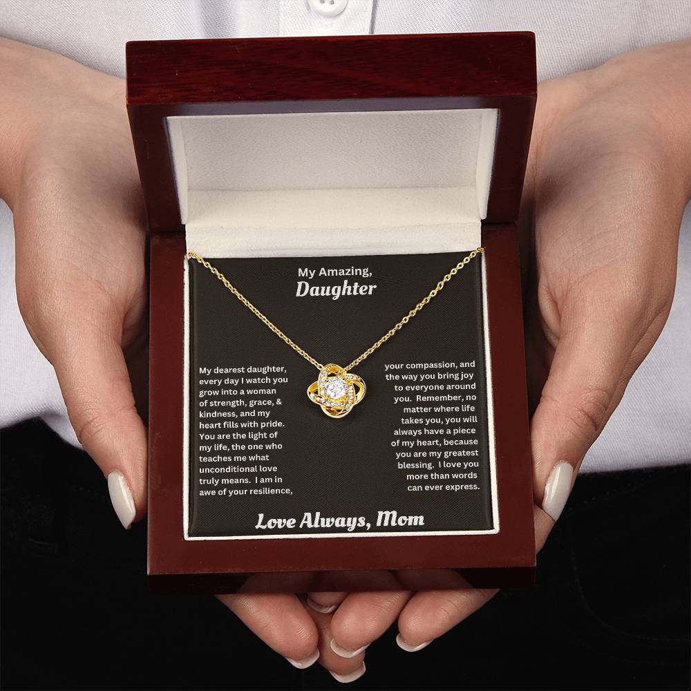 Hands holding Daughter gift from mom wit love knot necklace and special message in luxury box