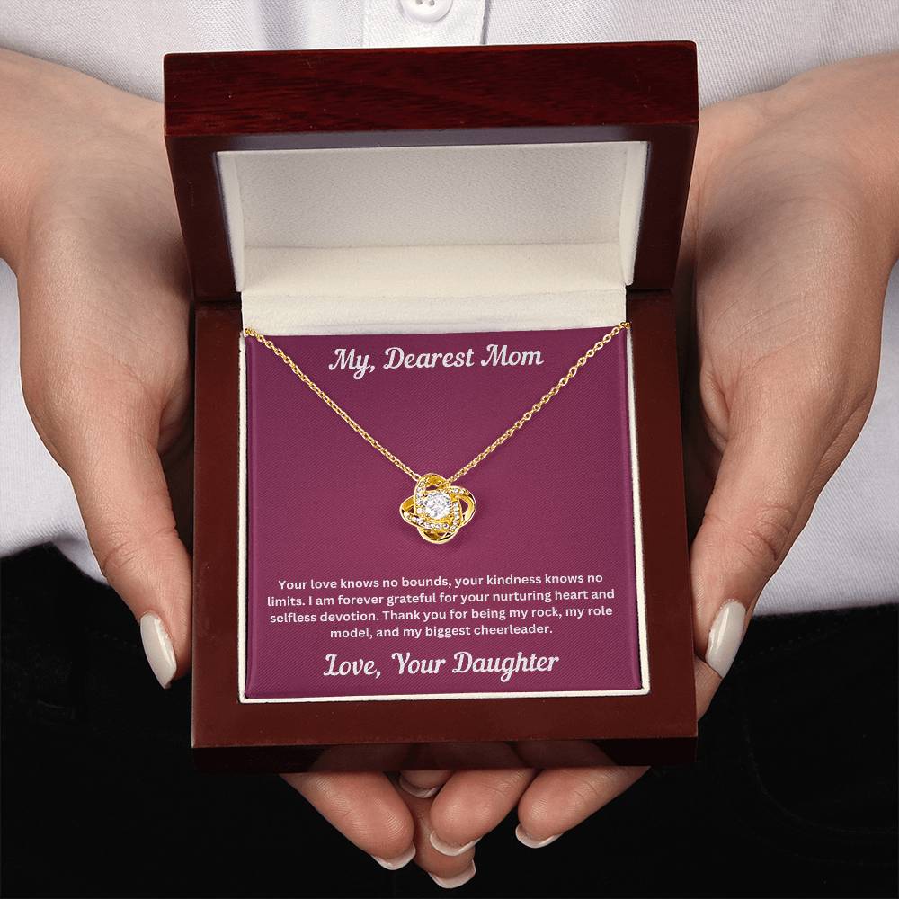 Two hands holdimg Mom gift from daughter with love knot necklace and special message in luxury box