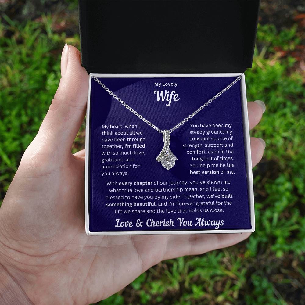 Hand holding Wife gift with alluring necklace and special message in a standard box