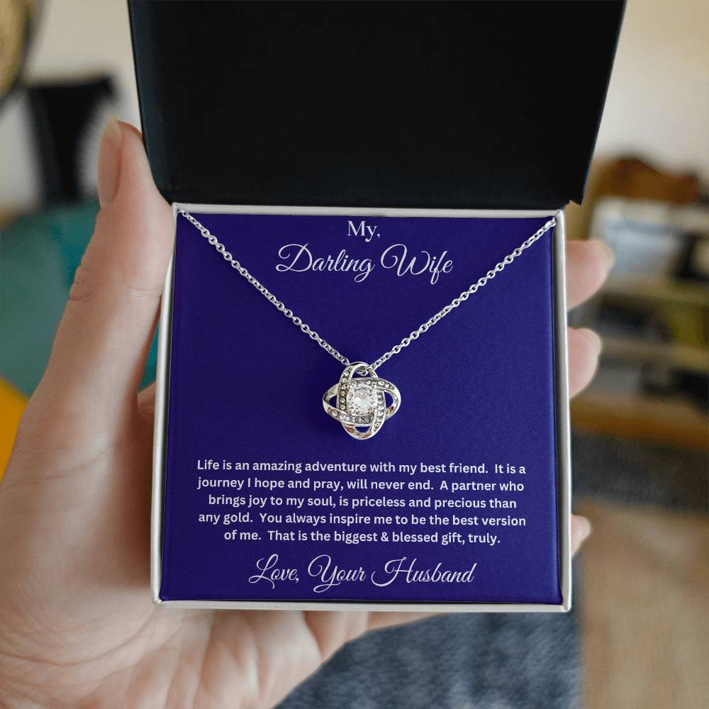 Hand holding Wife gift with love knot necklace and message in two tone box