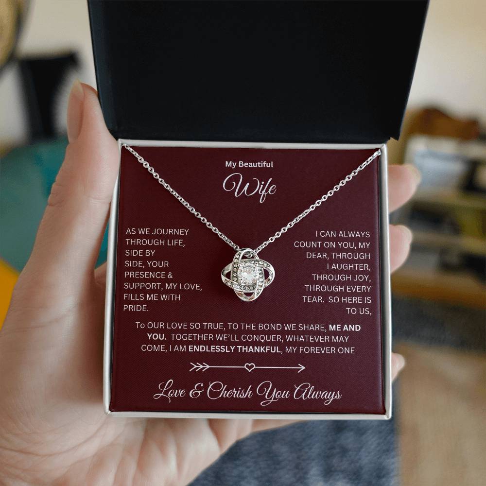 Hand holding Wife gift with love knot necklace and special message in a standard box