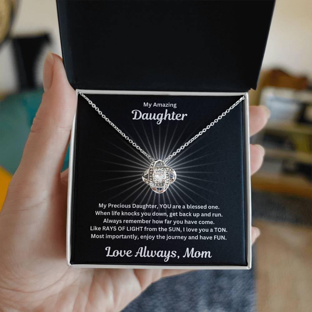 Hand holding Daughter gift from mom with beautiful love knot necklace and special message in a standard box