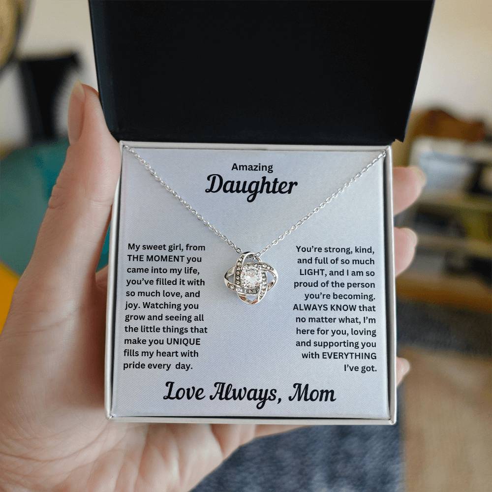 Hand holding Daughter gift from mom with love knot necklace and special message in standard box