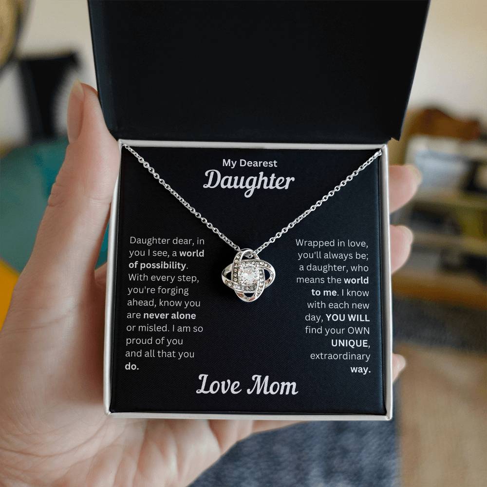 Hand holding Daughter gift from mom with love knot necklace and special message in a standard box