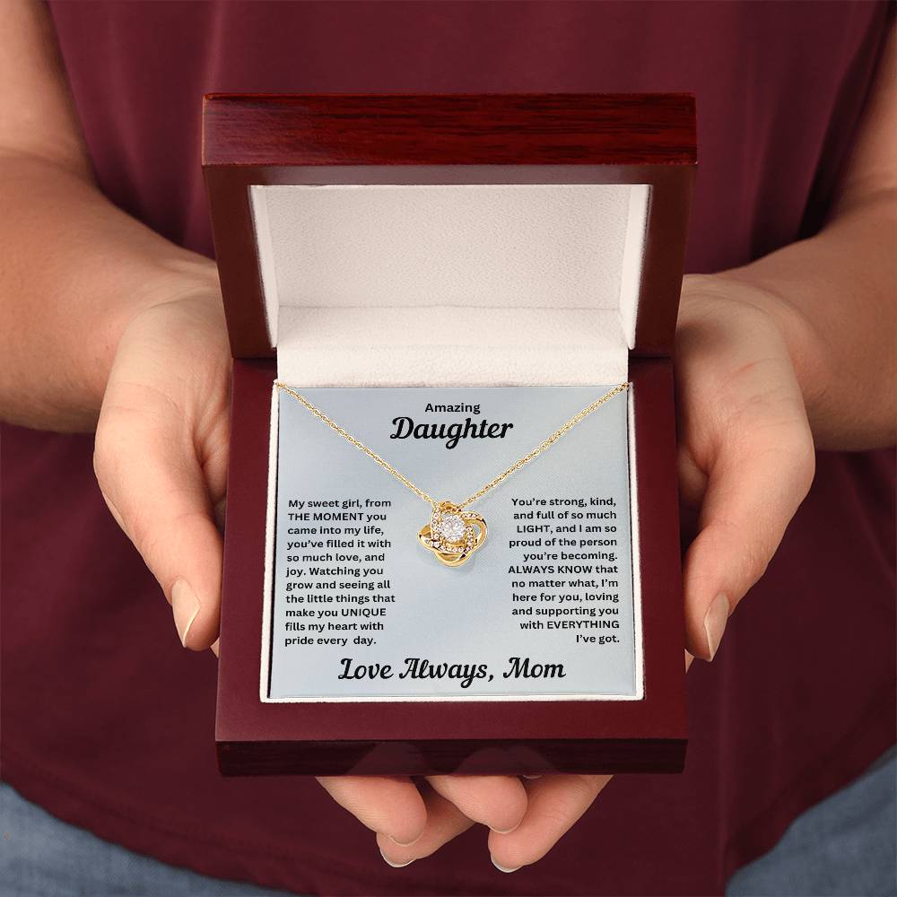 Hands holding Daughter gift from mom with love knot necklace and special message in luxury box