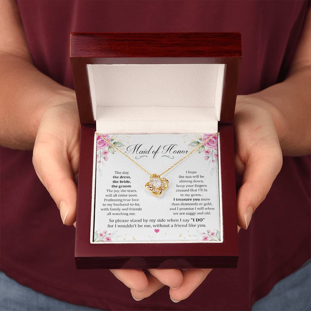 Two hands holding Maid Of Honor gift with love knot necklace and special message in luxury box