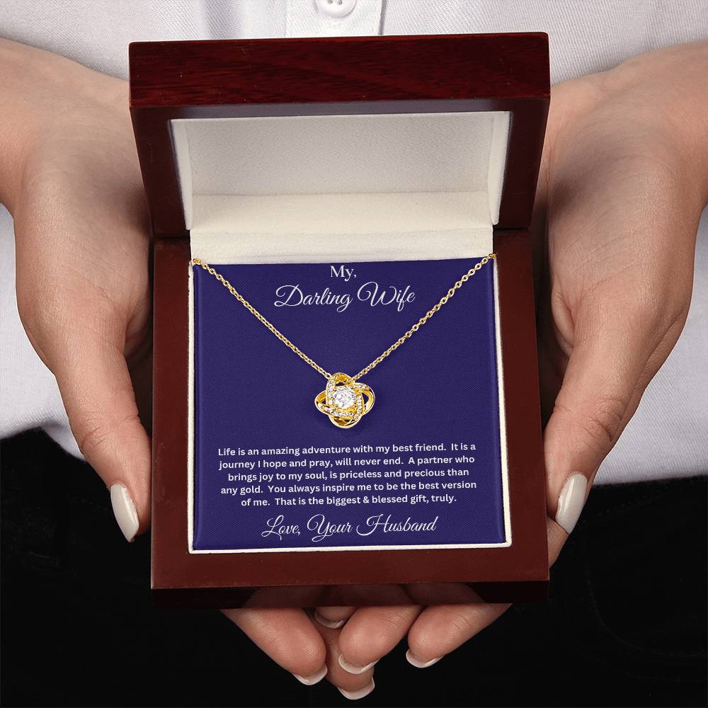 Two hands holding Wife gift with love knot necklace and message in luxury box