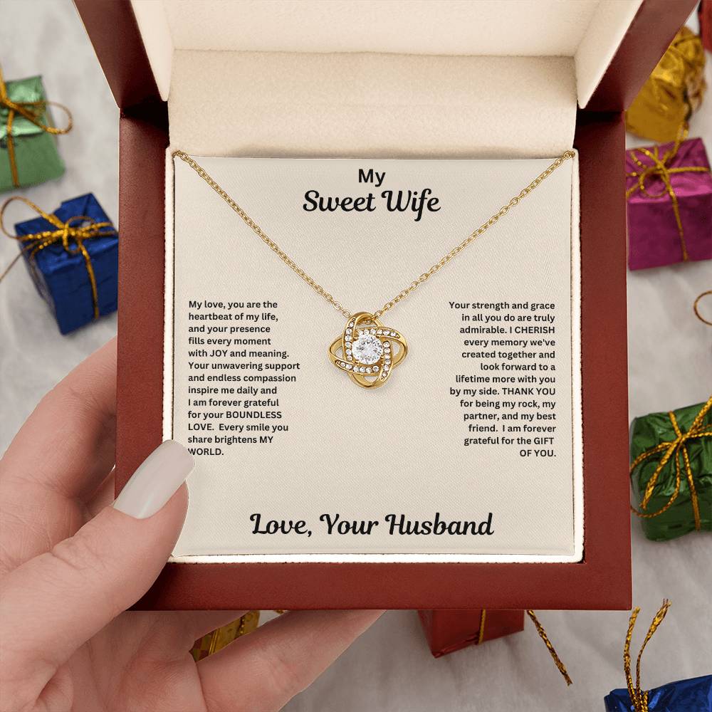 Hand holding Wife gift with love knot necklace and special message in luxury box