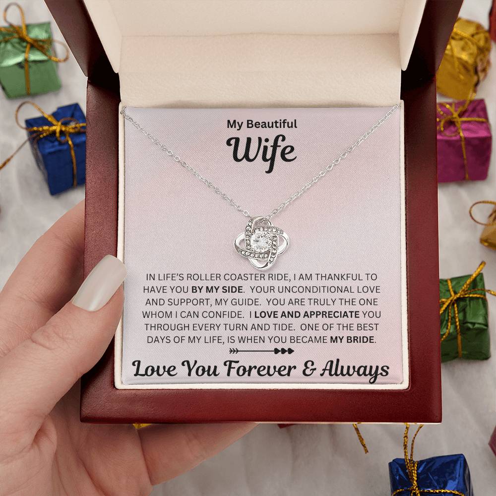 Hand holding Wife gift with love knot necklace and special sentiment in a luxury box