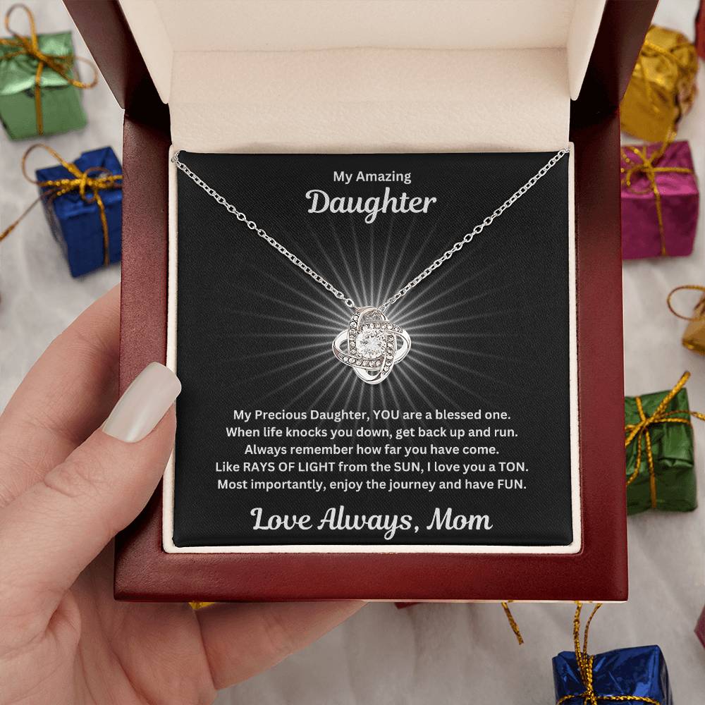 Hand holding Daughter gift from mom with beautiful love knot necklace and special message in a luxury box