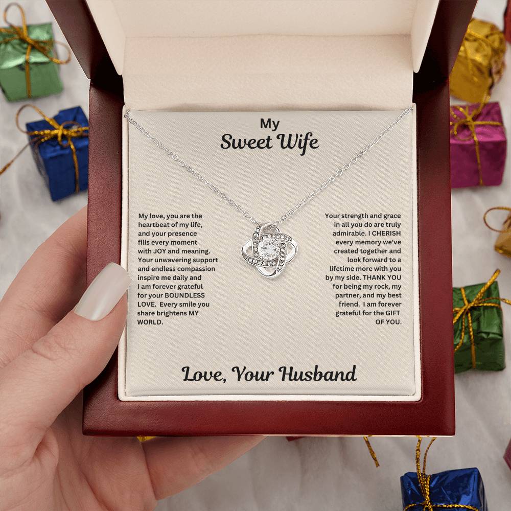 Hand holding Wife gift with love knot necklace and special message in luxury box