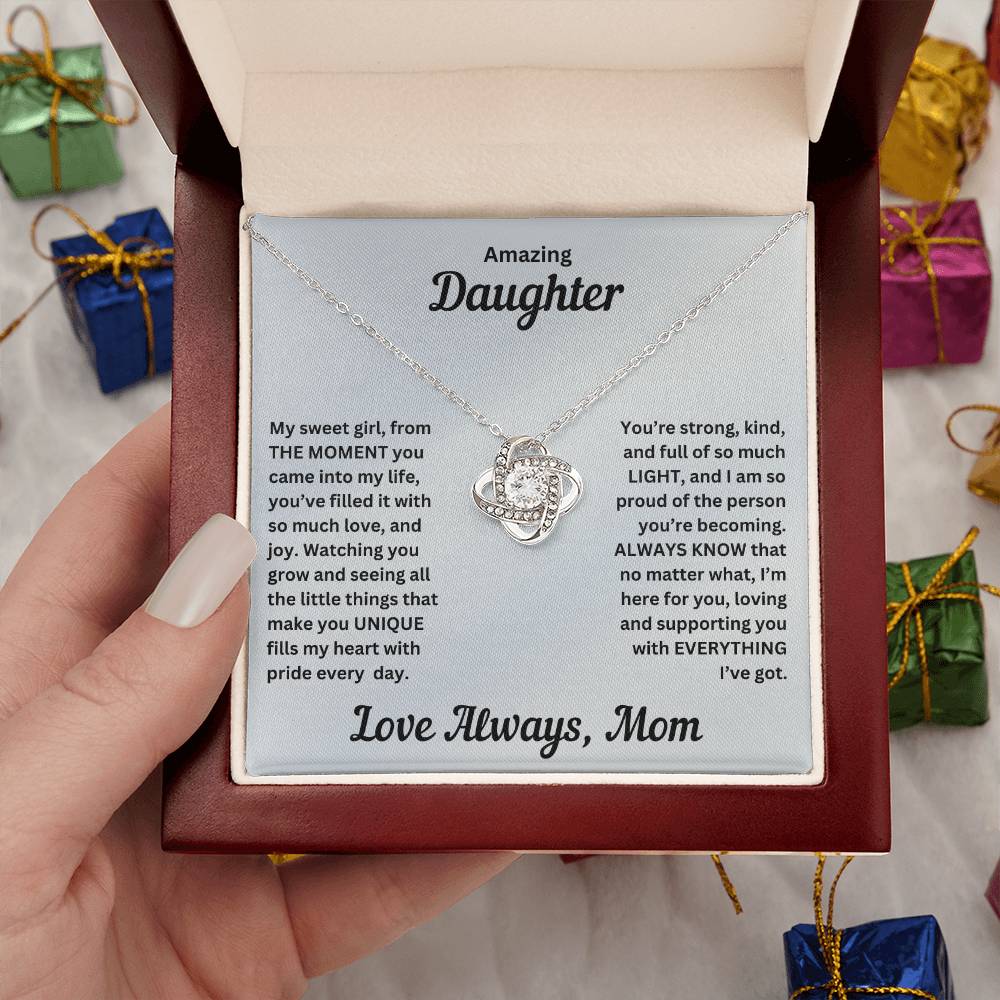 Hand holding Daughter gift from mom with love knot necklace and special message in luxury box