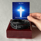Hand Holding Message Card With Men's Cross Bracelet Placed  On Top Of Mahogany Box